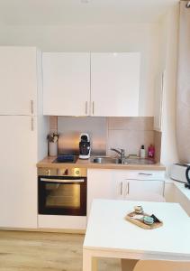 a small kitchen with white cabinets and a sink at L'écrin médiéval in Fougères +5 photos