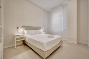a white bedroom with a bed and a window at Apartamentos Panda By Clabao in Pamplona