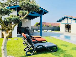 a couple of chairs sitting in the grass by a pool at Magnifique villa SEREN avec piscine in Arcangues