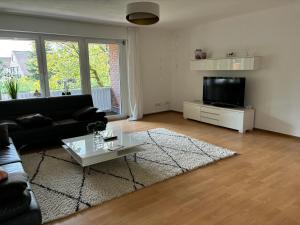 a living room with a black couch and a tv at FERIENWOHNUNG "Deichort" Meppen in Meppen