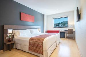 a bedroom with a bed and a desk and a window at Hotel Granada by Pierre & Vacances in Granada