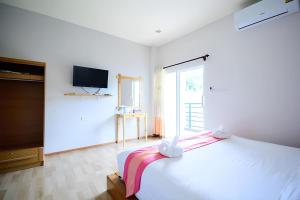 a white bedroom with a large bed and a tv at Sakura Yama Resort ซากุระ ยามะรีสอร์ท in Ban Huai Phai
