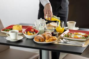 a table with a breakfast of croissants and other foods at The Queens Gate Hotel in London