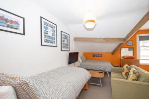 a bedroom with two beds and a couch and a television at The Green House Guest House in Liverpool