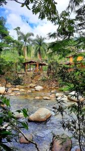a river with rocks and a house in the background at Finca Chévere in San Rafael +16 photos