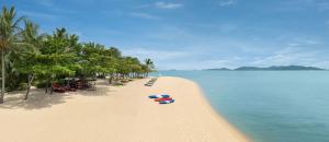 a sandy beach with boats on it next to the water at W Koh Samui in Mae Nam