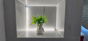a white vase with a green plant in a wall at Escape Residence in Vişeu de Sus