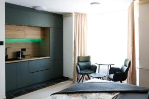 a kitchen with dark cabinets and chairs in a room at Studio Apartman Medonis in Pasuljište