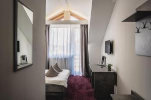 a room with a bed and a mirror and a window at Hotel Eden in Sibiu