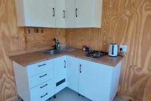 a kitchen with white cabinets and a sink at Quaint Cottage With Harbour Views in Cape Town