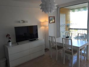 een woonkamer met een televisie en een tafel met stoelen bij Apartamentos Copacabana in Adeje