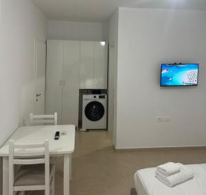 a white kitchen with a table and a washing machine at Vila TOLA in Durrës