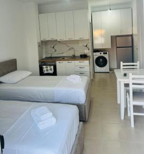 a room with two beds and a table and a kitchen at Vila TOLA in Durrës