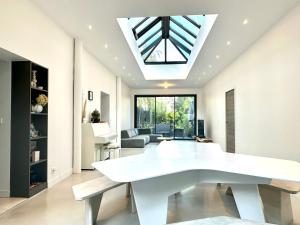ein Wohnzimmer mit einem weißen Tisch und einem Oberlicht in der Unterkunft Maison de Verdure proche de Paris in Bagneux + 23 Fotos