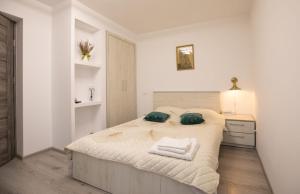 a white bedroom with a large bed with two pillows at Golden Mountain Flat- ADULTS ONLY in Petroşani