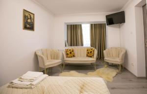 a room with two chairs and a bed and a television at Golden Mountain Flat- ADULTS ONLY in Petroşani