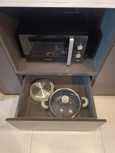 a microwave oven with a pot and pans in a drawer at GBA Condotel at Bonifacio Civic Center Tower in Manila