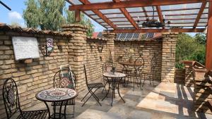 a patio with tables and chairs and a brick wall at Toscan Panzió in Gyál