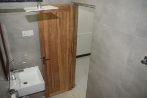 une salle de bain avec une porte en bois à côté d'un lavabo dans l'établissement Shenu Resort, à Mawella