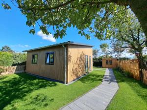 a tiny house in a yard with a fence at Have a nice stay! - Vakantiehuis Buitenplaats in Noordwijkerhout