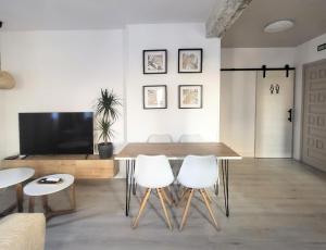 a living room with a wooden table and white chairs at Apartamentos Crispín Candela in Corella