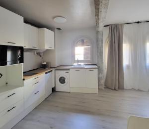 a kitchen with white cabinets and a washing machine at Apartamentos Crispín Candela in Corella