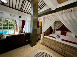 a bedroom with a canopy bed and a bathroom at Mangir Homestay in Banyuwangi