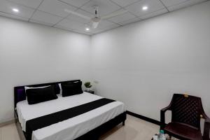 een witte kamer met een bed en een stoel bij SPOT ON Hotel Blu Moon in Noida +39 foto's