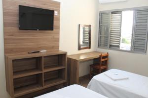 Schlafzimmer mit einem TV an der Wand und einem Bett in der Unterkunft Espigão Palace Hotel in Resende