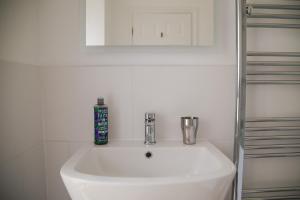 een witte wastafel in een badkamer met een spiegel bij Trigonos - Peaceful Lakeside Vegetarian B&B and Retreat in Eryri National Park in Caernarfon