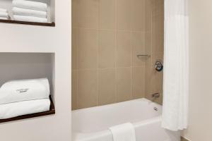 a bathroom with a tub and a shower with towels at Courtyard by Marriott San Jose Airport Alajuela in Alajuela City