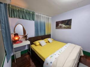 een slaapkamer met een geel bed en een spiegel bij Kanlayana Hostel in Ban Bang Toei (1)
