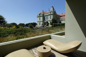 a balcony with a chair and a house in the background at Vila Foz Hotel & SPA - member of Design Hotels in Porto
