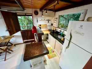 a kitchen with a refrigerator and a table in it at Chalé Romântico em Itacoatiara in Niterói