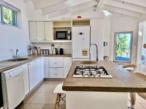 Una cocina con gabinetes blancos y encimera. en Cosy Beach Bungalow On Clifton, en Ciudad del Cabo