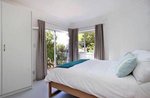 Un dormitorio con una cama y una ventana grande. en Cosy Beach Bungalow On Clifton, en Ciudad del Cabo