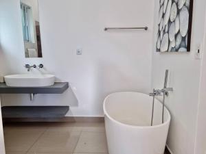 Un baño con bañera blanca y lavabo. en Cosy Beach Bungalow On Clifton, en Ciudad del Cabo 13 fotos más