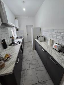 a kitchen with marble counter tops and a refrigerator at The Grand four bed getaway- Sleeps 9-free on street parking in Birmingham