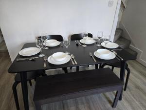 a black table with plates and wine glasses on it at The Grand four bed getaway- Sleeps 9-free on street parking in Birmingham