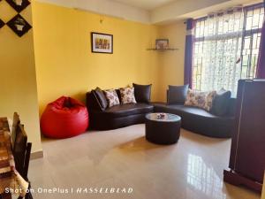 DispurDreams Abode 01 STUDIO APARTMENT的客厅配有沙发和红色的搁脚凳