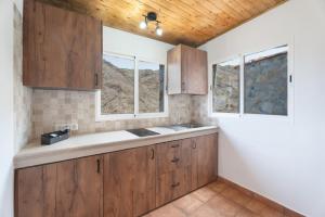 a kitchen with wooden cabinets and two windows at Vivienda vacacional La Era I in Vallehermoso +14 photos