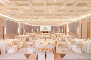 迈索尔ibis Styles Mysuru的宴会厅配有白色的桌椅和大标志 更多32张照片