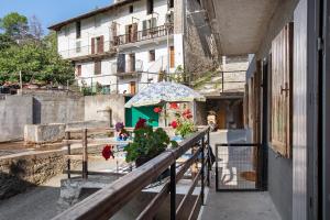 a balcony with a table with flowers and an umbrella at Maison Marcel Sarre in Aosta