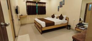 a bedroom with a bed and a television in it at Aquarius Resort in Pune