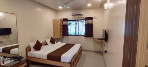 a hotel room with a bed and a television at Aquarius Resort in Pune
