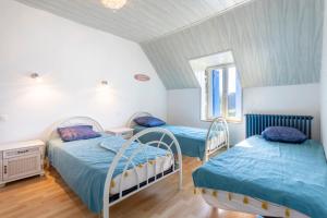 two beds in a room with white walls at Maison familiale 800m de la plage in Penmarcʼh