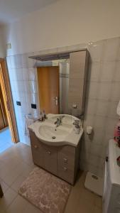 un bagno con un lavandino e un grande specchio di Appartamento a Fossato di Vico a Fossato di Vico