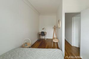 a white bedroom with a bed and a table at Flexliving - room - Lemoine in Paris