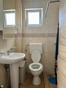 a bathroom with a toilet and a sink and two windows at Kronos in Budva