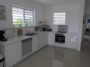a white kitchen with white counters and windows at Favvidea in Jan Thiel